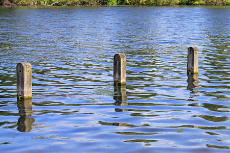 Three mooring wooden posts in lake waterの写真素材