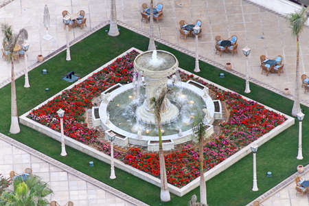 Foutain with red flowers in park gardenの写真素材