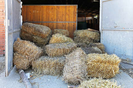 Square bale hay in front of stablesの写真素材