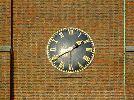 Roman style black clock at brick wallの写真素材