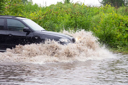 SUV vehicle driving fast through flood waterの写真素材