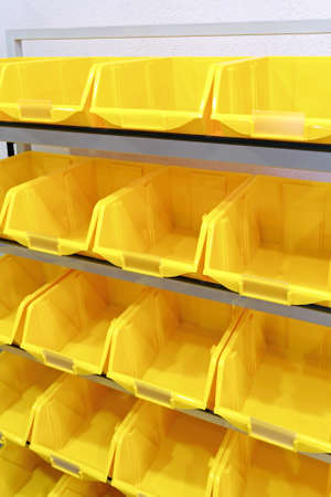 Yellow plastic racks for parts at wallの写真素材