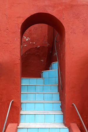 Blue stairs at red building with arch way