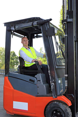 Bald Driver With Safety Vest in Forklift Cabin