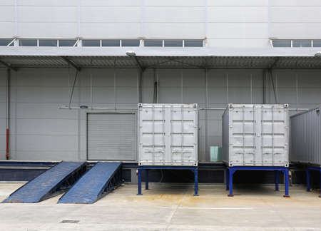 Silver Shipping Containers and Ramp in Front of Warehouseの写真素材