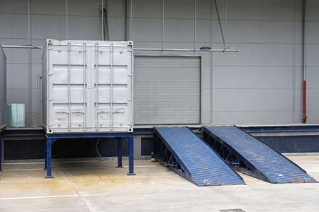 Loading Ramp and Silver Shipping Container in Front of Warehouseの写真素材
