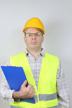 Middle Age Worker in Safety Gear Holding Checking Clip Board