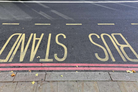 Yellow Letters Bus Stand Sign at Street With Double Red  Line