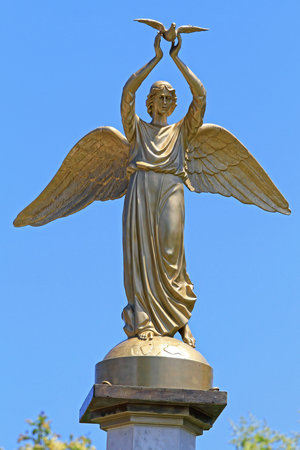 Stratoni, Greece - June 27, 2011: Winged Golden Lady Holding Dove Statue in Stratoni, Greece.のeditorial素材