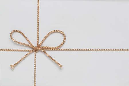 Small Golden String Bow at White Gift Wrap