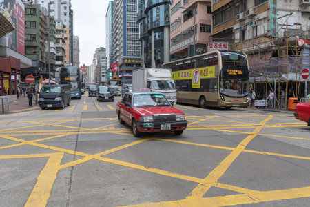 KOWLOON, HONG KONG - APRIL 22, 2017: Red Taxi Cab at Street Intersection in Kowloon, Hong Kong.