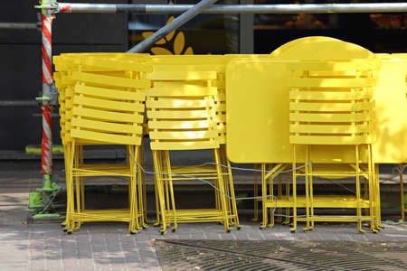 Bright Yellow Tables and Collapsible Chairs in Front of Cafeの写真素材