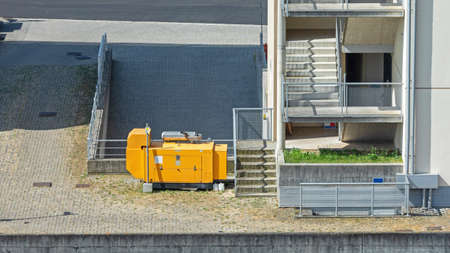 Big Yellow Electric Power Generator Behind Buildingの写真素材