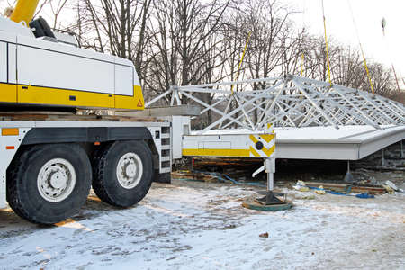 Crane Truck Lifting Heavy Steel Structure at Construction Siteの写真素材