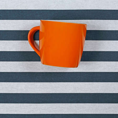 Big Orange Ceramic Coffee Mug at Striped Background