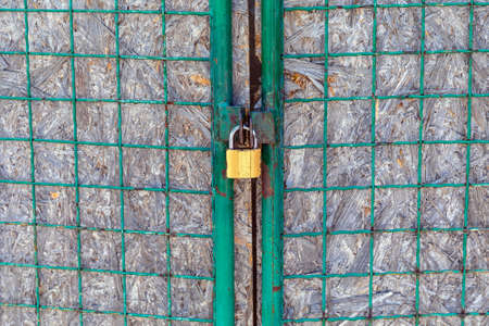 Locked Brass Padlock at Mesh Wire Gateの写真素材