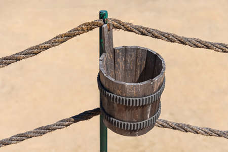 Brown Wooden Bucket Hanging at Outdoor Rope Fenceの写真素材