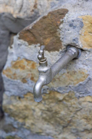 Silver Tap Water Faucet at Old Stone Wallの写真素材