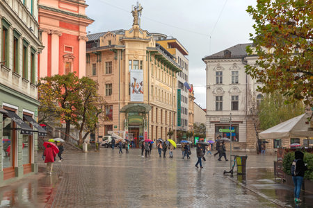 Ljubljana, Slovenia - November 04, 2019: People Walking With Umbrellas at Wet Cobbled Streets Rainy Day in Capital City Centre.のeditorial素材