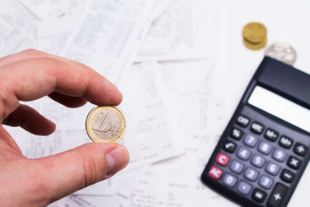 hand holding euro coin and calculator in background