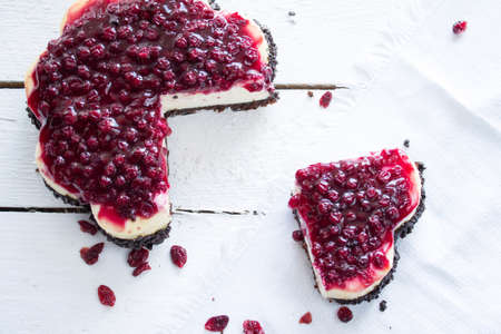 Piece of cheesecake with cranberries. Composition on white wooden boardの写真素材
