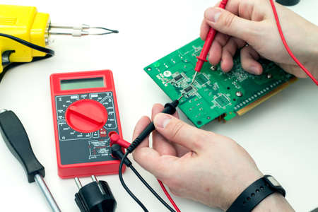Electrician checks electronic hardware with a multimeter in the workshop