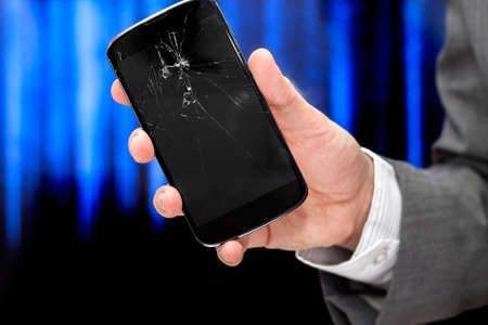 Businessman shows broken smartphone with crashed screen.の写真素材