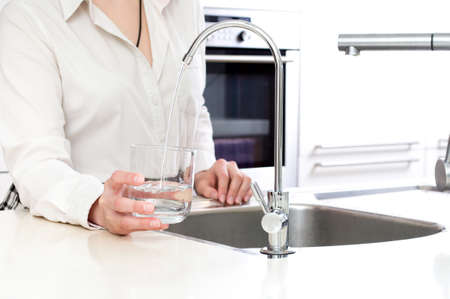 Woman pours fresh clean water into the glassの写真素材