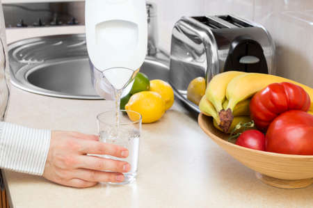 Man fills glass with clean water from filter jugの写真素材
