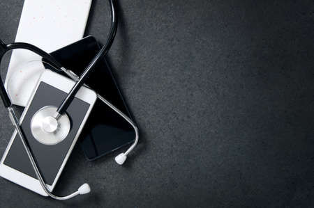 Smartphones and a stethoscope on the desk. Concept of diagnose faults in the phoneの写真素材