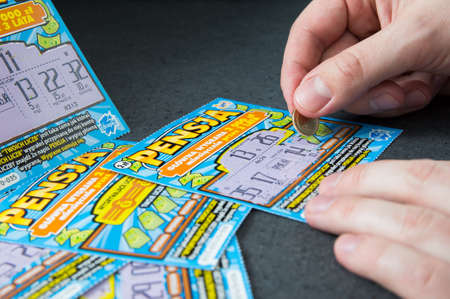 WROCLAW, POLAND -  NOVEMBER 30th, 2016: Man scratches Polish lottery scratchcard. Scratchcard is a small card, where areas contain concealed information which can be revealed by scratching off an opaque covering.のeditorial素材