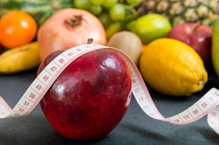 Apple and measuring tape over fruity backgroundの写真素材