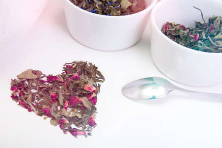 Heart arranged with green tea leaves and different kind of herbs on wooden tableの写真素材