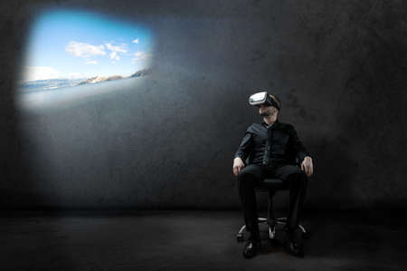 Man with Virtual Reality headset is sitting on chair on wheels in some hangar