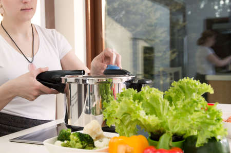Woman uses pressure cooker to cook a meal. Conception of healthy nutrition.の写真素材