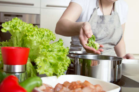 Woman puts vegetables into the pot. Conception of healthy food preparing.の写真素材