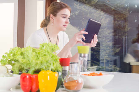 Woman checks the recipe on her tablet.