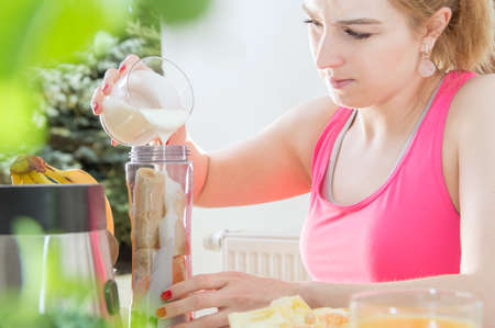 Athletic woman holds a yogurt on the table with healthy foodの写真素材
