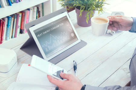 Heat energy consumption application for tablet pc. Man holds phone.の写真素材