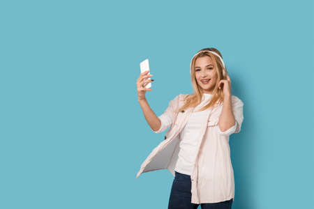 Cheerful blonde girl with smartphone smiling and listening to the musicの写真素材