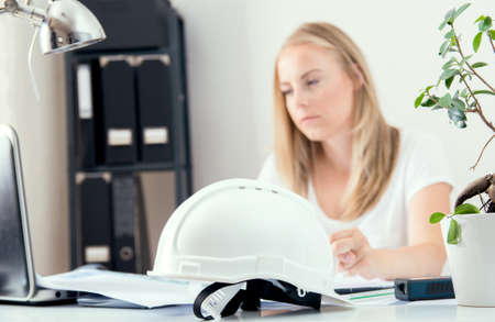 Architect's white helmet in the central point and a woman architect in the backgroundの写真素材
