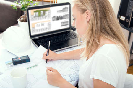 Young female architect is working at her new project at home officeの写真素材