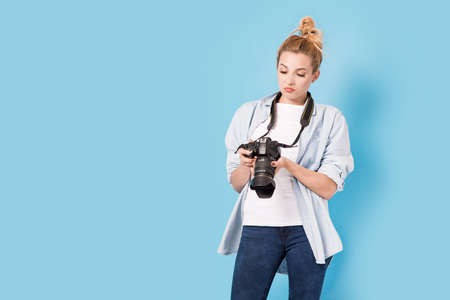 Woman photographer is satisfied about her work. Model isolated on a blue background with copy spaceの写真素材