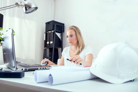 Blonde female architect works at her new plans and sketches