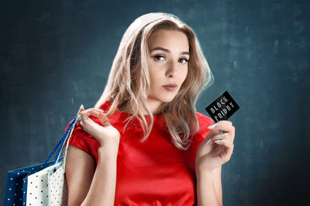 Beautiful woman with shopping bag and black Friday cardの写真素材