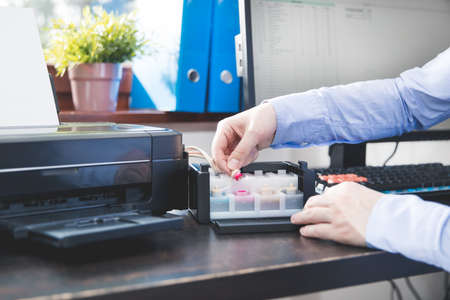 Businessman checks how much ink has been left in the printer's containerの写真素材