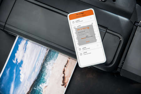 Smartphone connected with wireless photo printer sending file to print