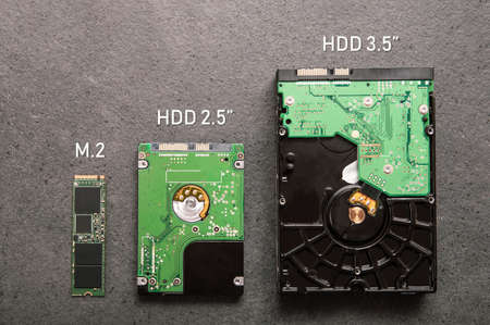 Three drives arranged on a stone slab. Comparison of SSD M.2 drive with HDD 2.5 and 3.5