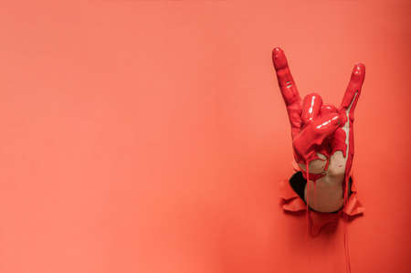 Rock sign gesture painted with red paint coming out of wall