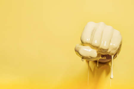 Fist painted with yellow paint pierces the wallの写真素材